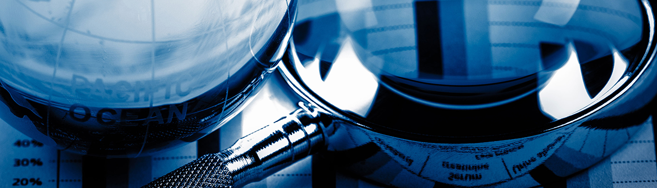 A magnifying glass beside a glass globe laid over a document with charts.
