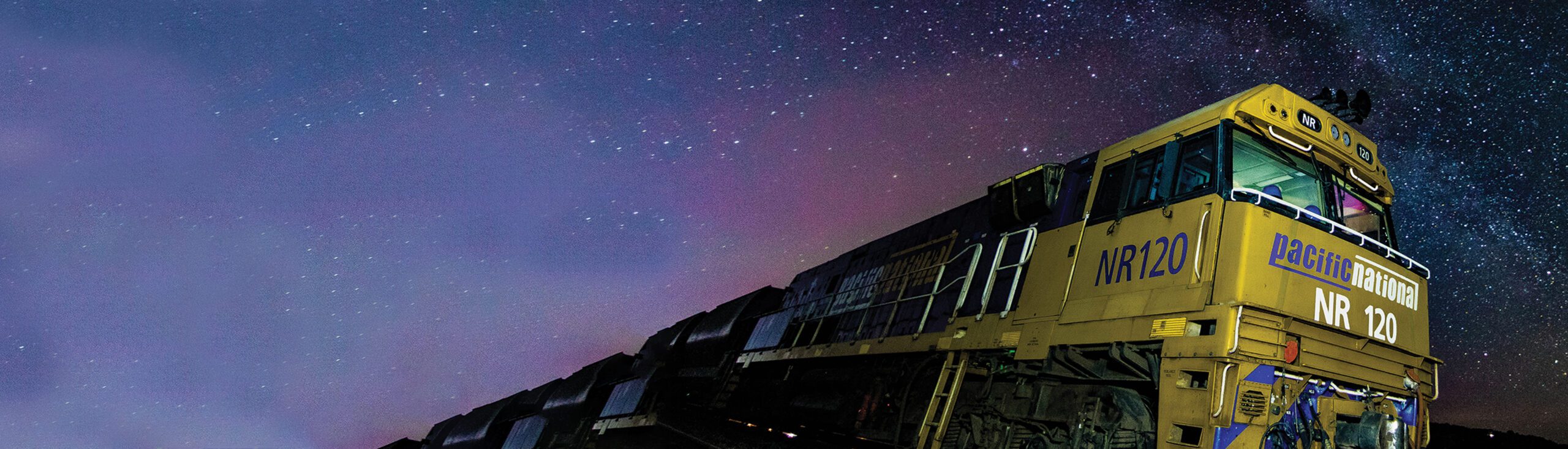 A moving passenger train under a starlit night sky.
